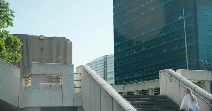 Concrete stairway is hosting commuters appearing from sides and climbing steps to reach overpass