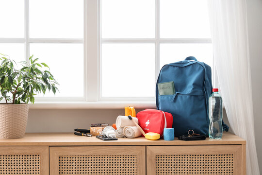 Emergency backpack with necessities on chest of drawers near window in room