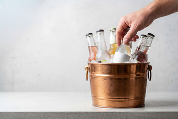 Plakat Hand taking a cold bottle of hard seltzer from a copper ice bucket at a party