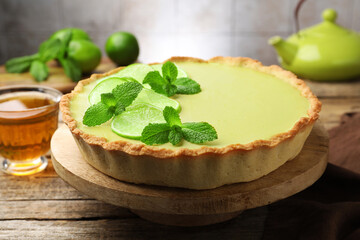 Tasty lime pie with fruit slices and mint leaves on wooden table, closeup © New Africa