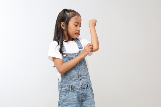 A 7-8 year old Asian child scratches his itchy hand due to mosquito bites or dermatitis, scabies, allergy symptoms, or malaria.
