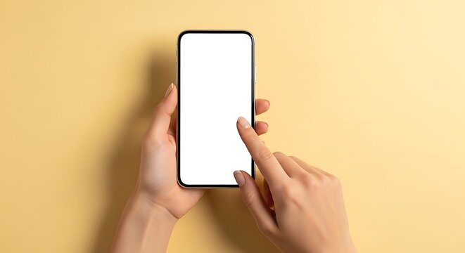 Close-up overhead shot of a person's delicate hands holding a modern smartphone with a blank white screen, finger poised to touch, against a soft pastel yellow background.