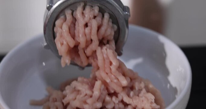 Woman making minced meat with grinder at black wooden table indoors, closeup. Camera moving in
