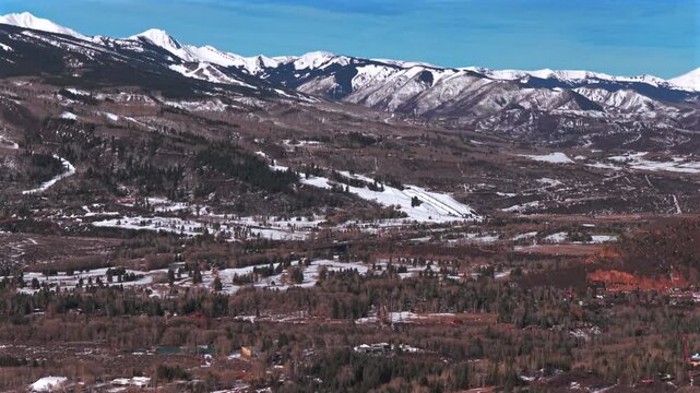 Buttermilk Ski resort Snow League winter sunny blue sky bluebird morning aerial drone Colorado Aspen Snowmass town ski trail runs Maroon Bells Wilderness Aspen Airport forward pan up motion
