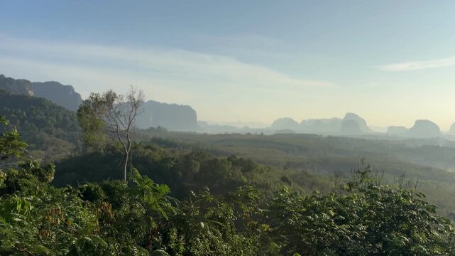 Early sunrise scene over misty valley and limestone hills at Din Daeng Doi in Krabi Thailand with soft sunlight, layered forest, and calm tropical landscape view