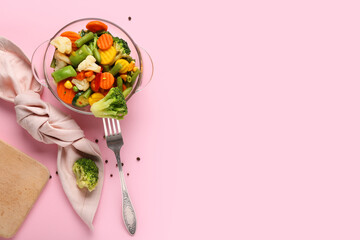 Colorful mixed vegetables in glass bowl with fork on pink background, healthy vegetarian meal, steamed broccoli, carrots, cauliflower, corn and green beans with copy space © Pixel-Shot