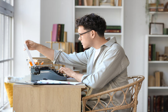 Male screenwriter using typewriter at table in office