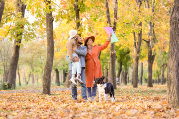 Fototapeta premium Happy family with kite and dog in autumn park