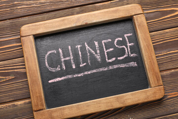 Chalkboard with text CHINESE on wooden background