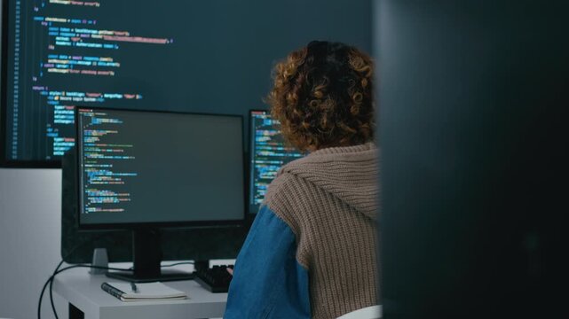 Asian female software engineer and diverse developers working on programming code on computer screens in a modern office. Concept of AI development, coding, and future technology.