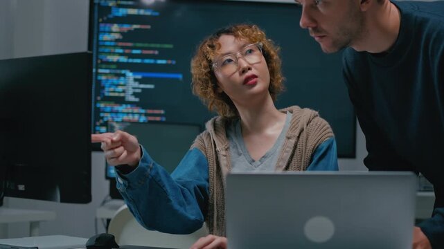 Asian female software engineer and diverse developers working on programming code on computer screens in a modern office. Concept of AI development, coding, and future technology.