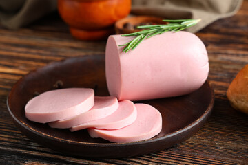 Sliced bologna sausage with rosemary on rustic plate over wooden table, close up of deli luncheon meat for breakfast, snack or sandwich preparation © Pixel-Shot