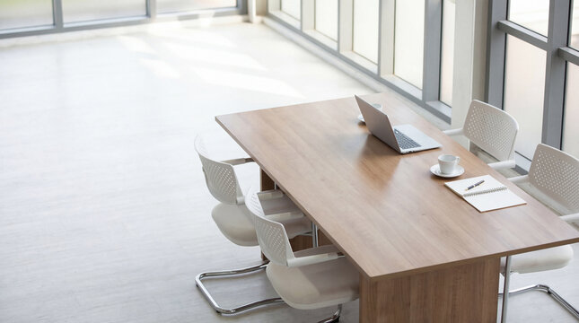 High angle photograph of a minimalist modern office meeting table with a single laptop and coffee for focused work.