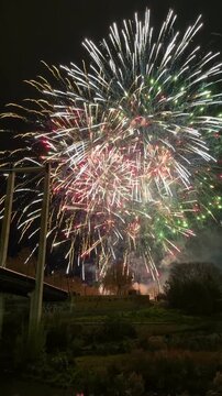 Nit del Foc Fireworks illuminating the night sky over a bridge and river, creating colorful reflections during the traditional Fallas de Valencia festival