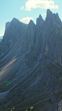 Vertical screen Aerial Seceda Dolomites Jagged Peaks Under Bright Sky, Steep Rocky Ridge, Deep Shadows On Scree Slopes, Textured Rock Faces, Crisp Midday Light, Remote Alpine Atmosphere