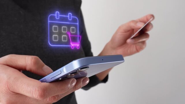 Shopping plan on a calendar. Businesswoman holding a bank card while holding a smartphone with a virtual calendar icon and shopping cart.