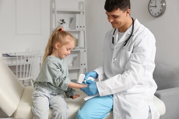 Obraz premium Male pediatrician measuring temperature of little girl with infrared thermometer in clinic