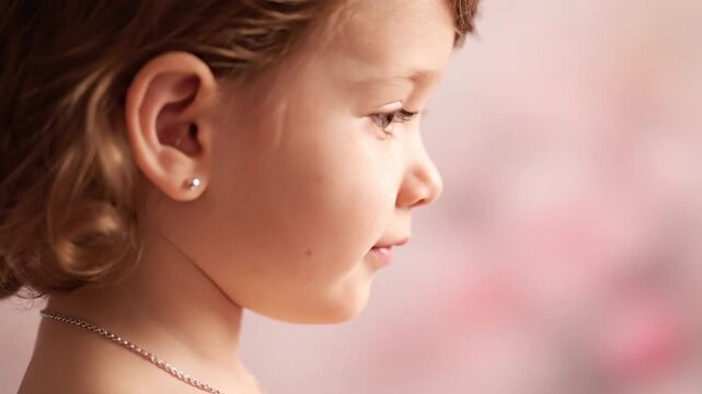 Close-up profile of a young child with an earring and necklace