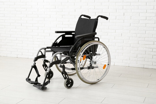 Empty wheelchair near white brick wall