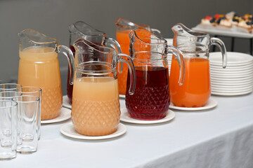 Assorted catering beverage station with fruit juice and berry mors in glass pitcher on buffet table for event with no people and copy space for menu © Tatiana