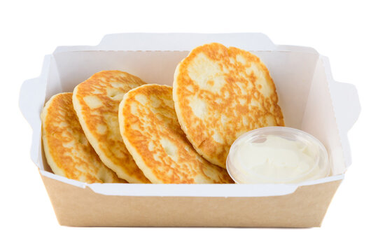 Sweet thick pancake with sour cream in craft paper take out box on white background side view close up with copy space delicious savory breakfast