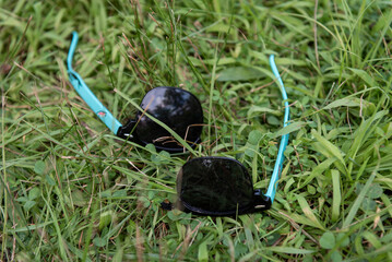 Naklejka premium A pair of broken sunglasses laying in the grass