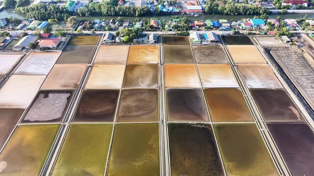 Top-down drone footage of salt evaporation ponds forming colorful geometric patterns. Abstract textures and structured layout suitable for background use.