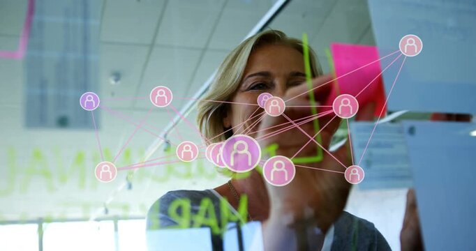 Manager starting writing on glass, connecting pink nodes, placing sticky notes to map business plan