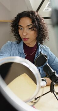Vertical video: Non-binary artist in loft angling mirror, ring light for shot, showing makeup brush