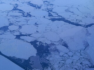 Majestic sunset over the snow-covered mountains and ice floes of the East Greenland coast, viewed from above.