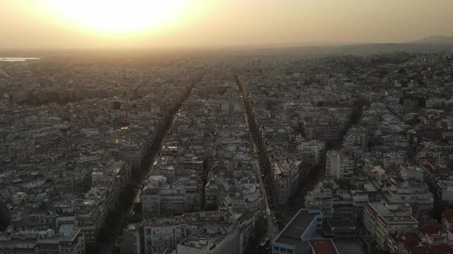 Sweeping aerial shot of thessaloniki city, greece, showing dense buildings and streets at sunset