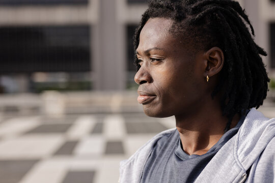 African american man gazing toward left edge on patterned tiled rooftop wearing gray hoodie