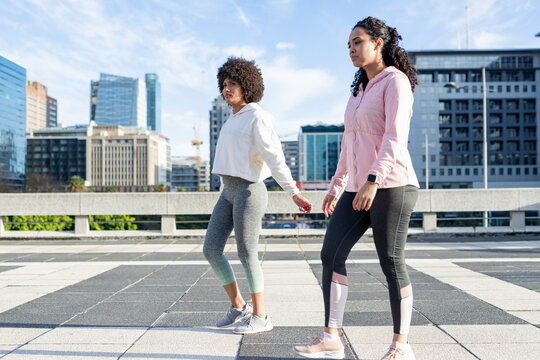 African american friends in sportswear walking on rooftop overlooking skyline