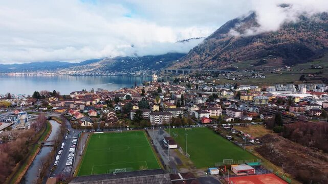 Aerial: Villeneuve cityscape and Lake Geneva during the day in Canton of Vaud, Switzerland, parallax drone shot