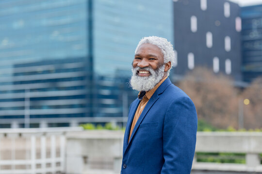 African american man in blue blazer and shirt standing smiling on terrace with railing