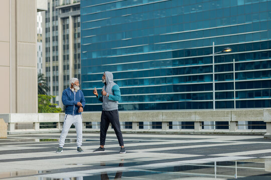 Senior african american friends chatting in athletic hoodies and sweatpants on city square