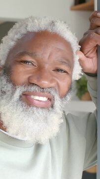 Vertical video: Glancing right, man softening to smile while gripping frame, wearing green sweater