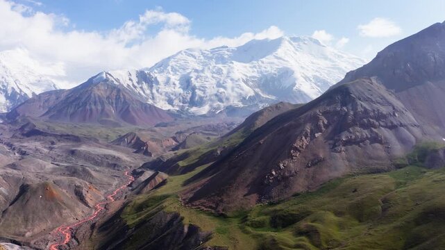 Incredible aerial 4K flying drone footage of mountain river with tributaries surraunded green hills deep in Pamir mountains with Lenin peak 7134m, Kyrgyzstan, Central Asia