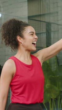 Vertical video: Celebrating point, woman in red top on court high-fiving teammate with paddle