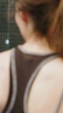 Vertical video: Camera framing racerback woman responding, turning to partner with paddle on court