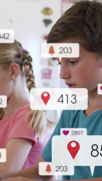 Vertical video: Boy glancing up, smiling as notif badges multiplying while girl writing in class