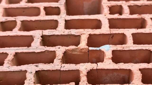 Close-up of hollow ceramic bricks texture. Symmetrical pattern of clay building blocks in horizontal pan movement. Industrial masonry material.
