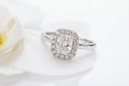 Radiant cut diamond engagement ring with halo setting on white flower petals