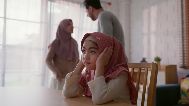 Adorable Muslim girl covering ears while parents argue in background. 