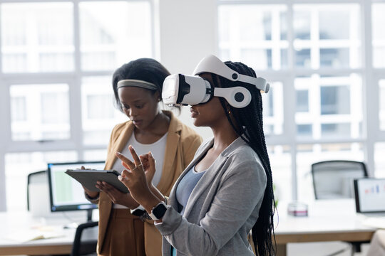 African American coworkers demonstrating virtual reality with headset and tablet in office space