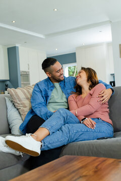 Couple leaning on gray sofa in modern home living area with wooden coffee table