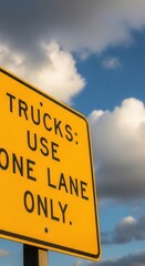 Fototapeta premium Trucks Use One Lane Only Road Sign Against Cloudy Sky