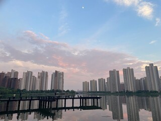 Obraz premium Cityscape Lake reflection High-rise apartments Sunset sky Moon Boardwalk
