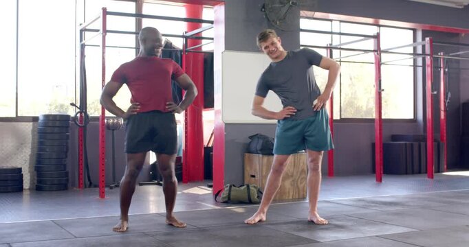 Male coach and trainee performing side bends with hip opening stretches warming up by pull-up rig
