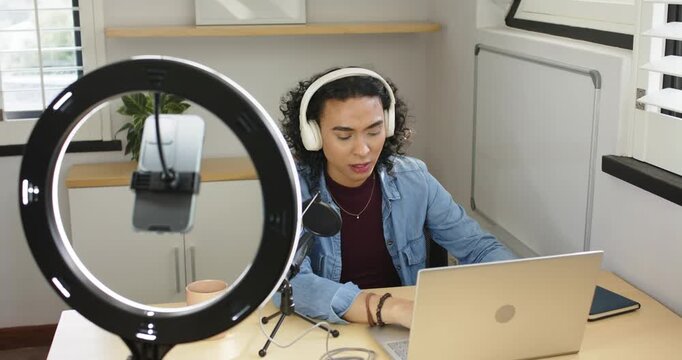Non-binary streamer turning on ring light, typing on laptop and speaking into mic for studio stream